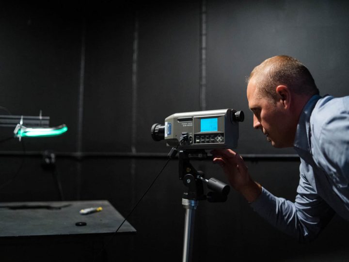An engineer works in a light lab and looks through a light meter