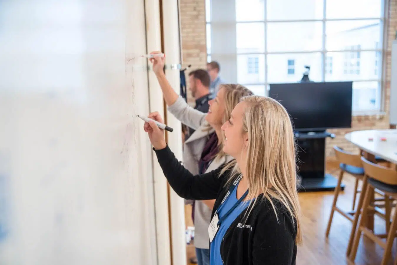 Two women draw their ideas on a whiteboard