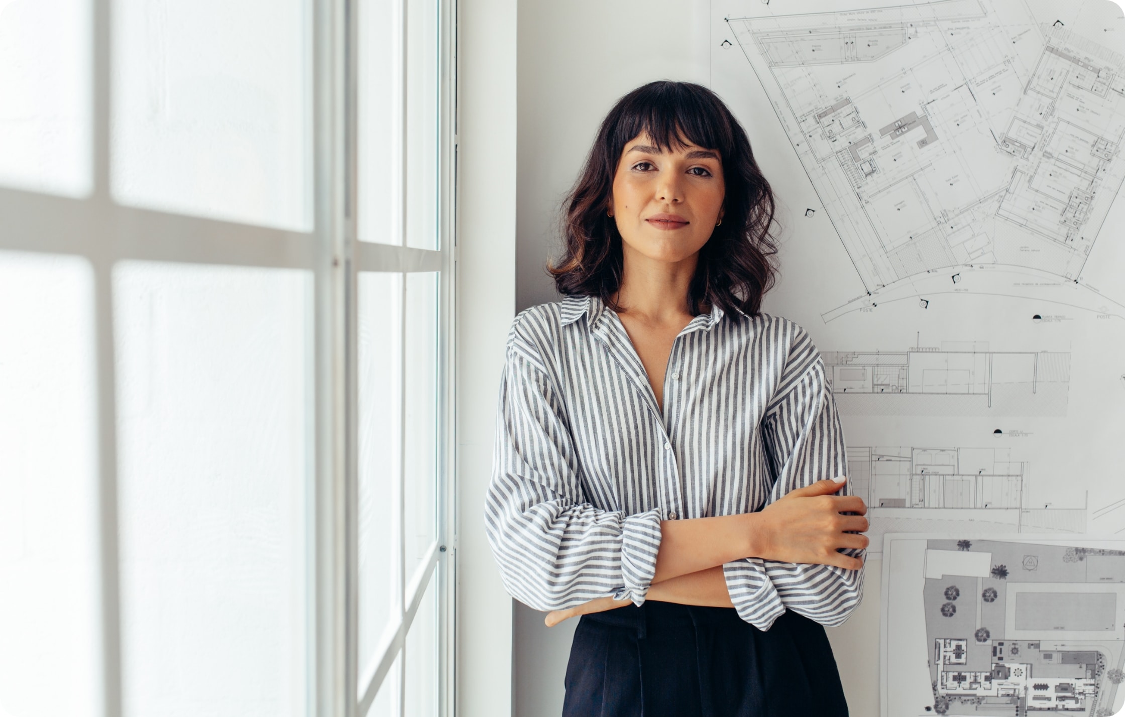 A woman architect leaning against wall of designs