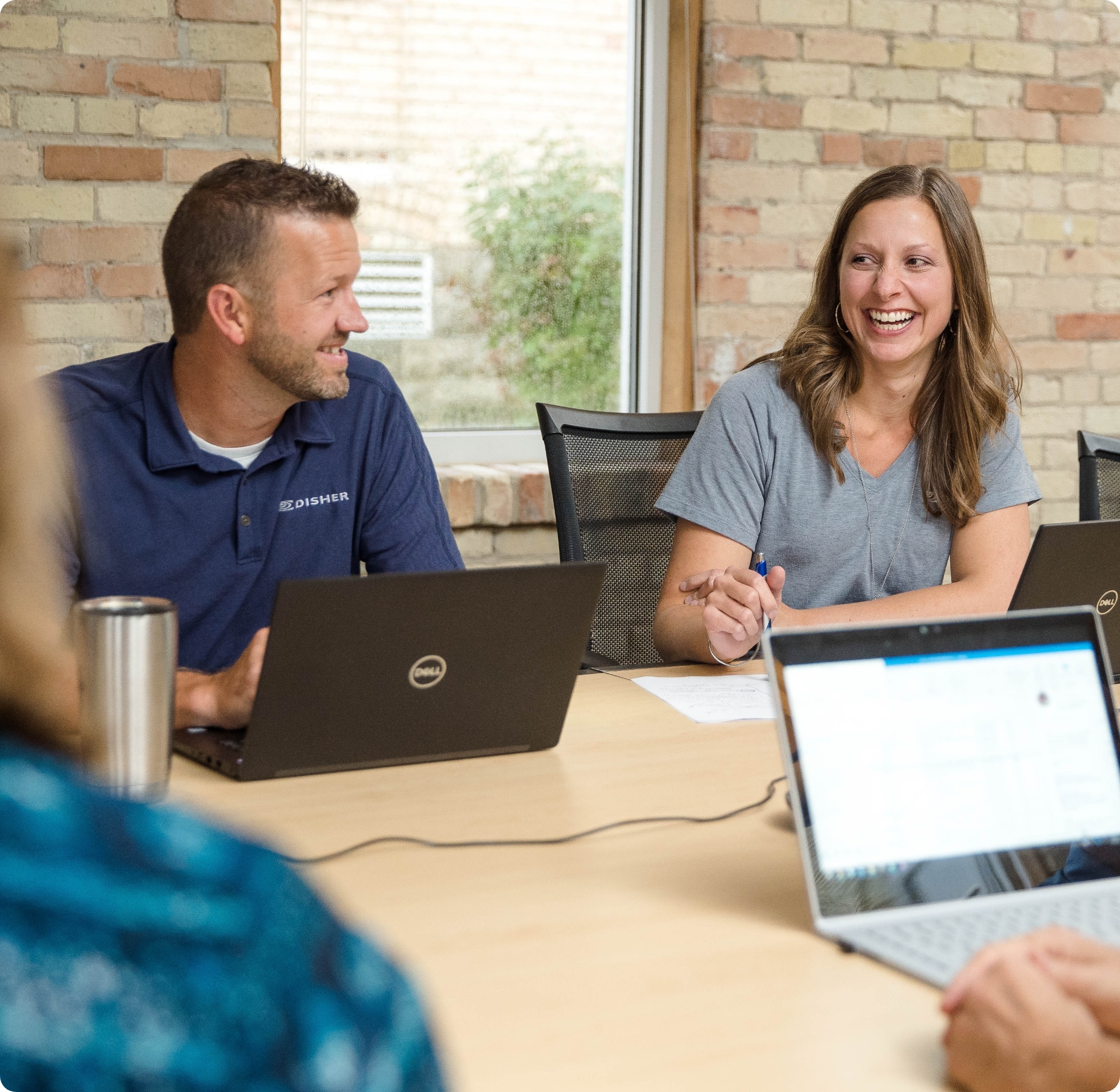 A man and woman smiling and laughing in a meeting