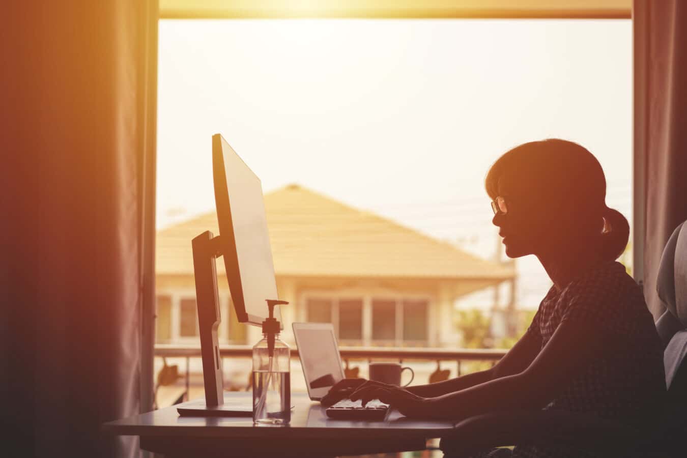 A women working from home at her computer as the sun sets