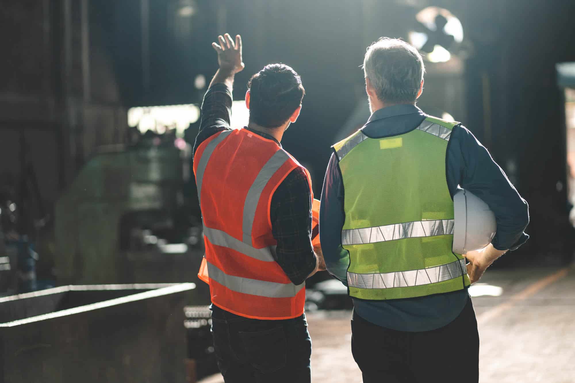 Two constructions workers look and point at work being done
