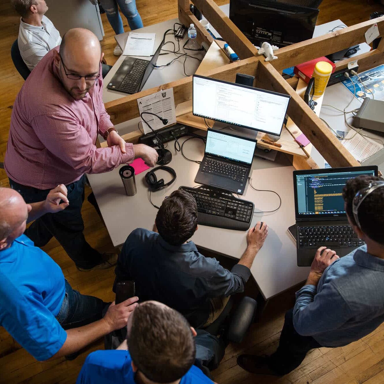 Software developers standing around a computer