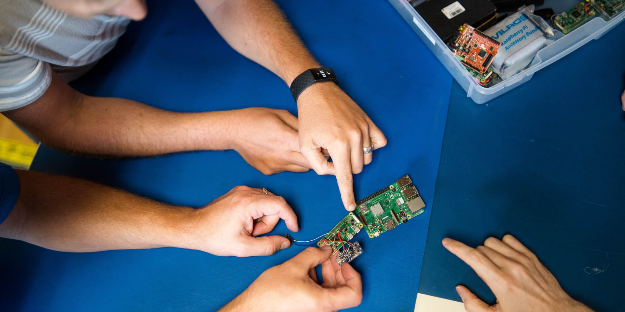 Electronics team pointing at a circuit board