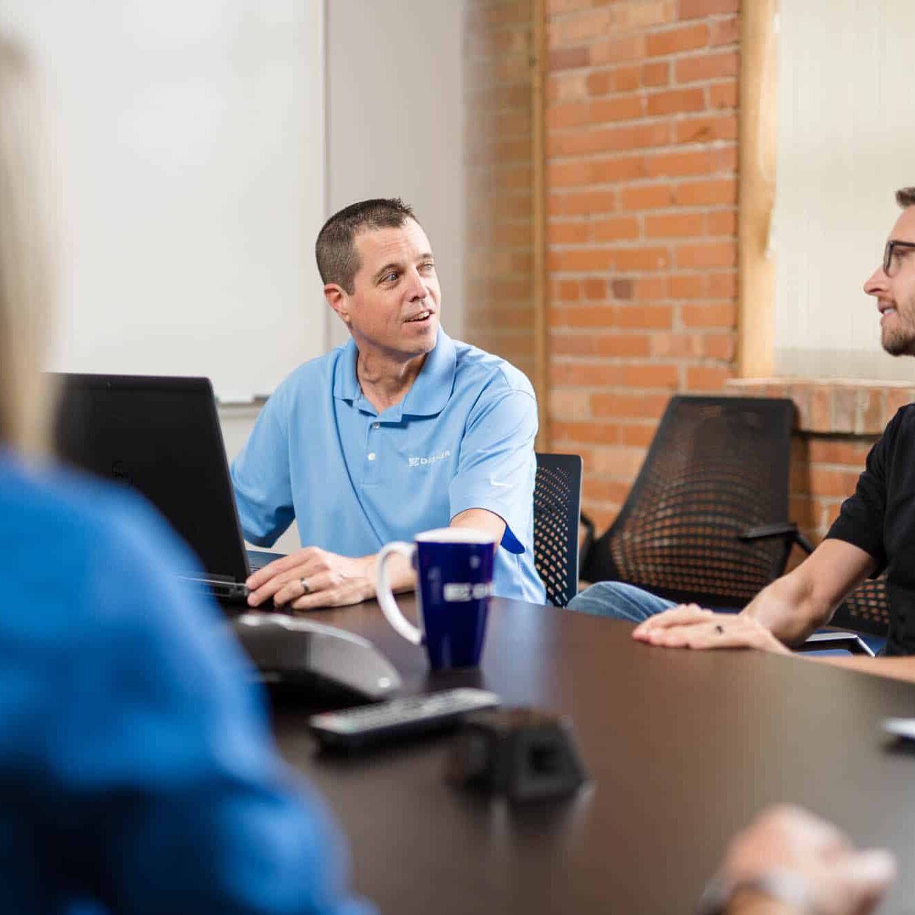 A project manager sits with engineers to discuss a project.