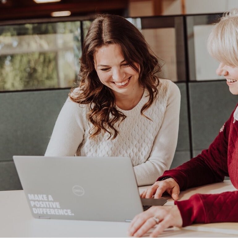 Two recruiters look together at a laptop